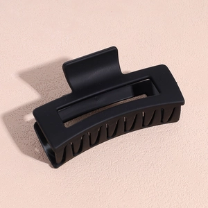 Détail de la grande pince à cheveux noir mat avec un design rectangulaire creux minimaliste