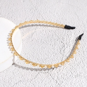 Detail van de elegante gouden haarband met amberkleurige en witte kristallen kralen