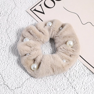 Gros plan sur un chouchou élégant en peluche beige avec des perles blanches