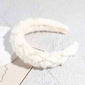 Detail of plush white headband with elegant pearl patterns on a textured background