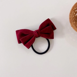 Detail of a deep burgundy velvet bow hair tie with a durable black elastic band