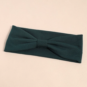 Elastic dark green ribbed knit sports headband featuring a stylish knotted bow design