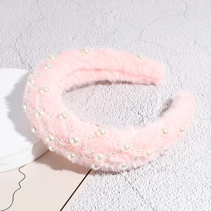 Detailed view of pink plush headband featuring elegant white faux pearls and soft fur texture