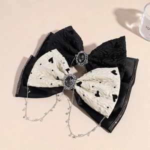 Double-layered bow hair clip with rhinestone tassels and star pendants on beige surface