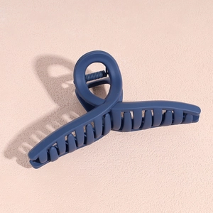 Détail d'une grande pince à cheveux bleu marine mat en acrylique sur fond rose