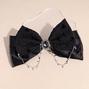 Detail of black bow hair clip with rhinestone tassels and star pendant on lace