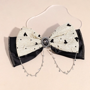 Detail of a double-layered bow hair clip with rhinestone center and hanging star tassels
