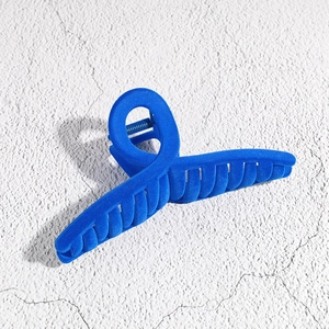 Detail of royal blue flocked hair claw clip with velvety texture and curved geometric design