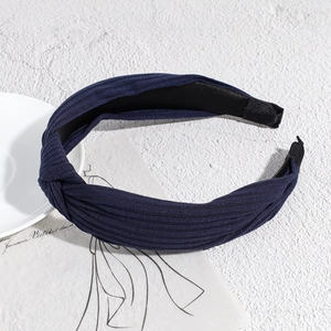 Detail showing deep blue knotted knitted headband with a soft ribbed texture on stone