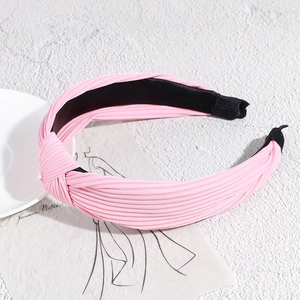 Detail showing pink pleated fabric headband with knotted design and non-slip lining
