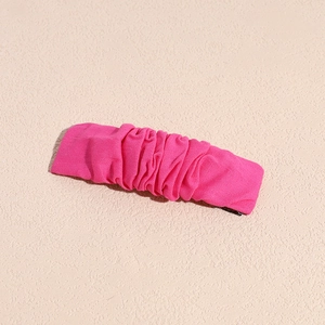 Close-up of rose red pleated fabric hair clip showing detailed textile texture and design