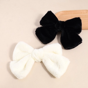 Plush bow hair clips in black and cream white with soft faux fur texture for women