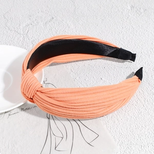 Close-up of orange-pink knitted headband with ribbed texture and central knot detail