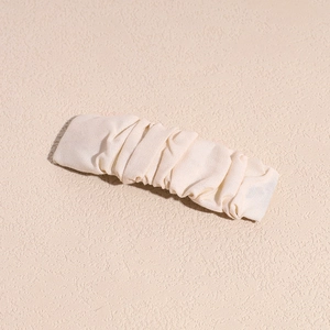 Detail of cream pleated fabric hair clip with elegant mesh texture and rectangular design