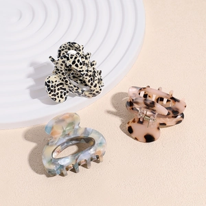 Three acetate hair claws in marble and tortoiseshell patterns on a textured background
