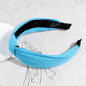 Detailed view of light blue knotted headband with ribbed texture on a decorative backdrop