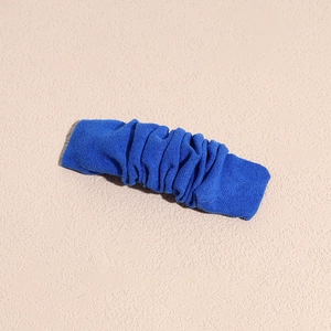 Detail of Klein blue ruched fabric hair clip with a minimalist textured fold design