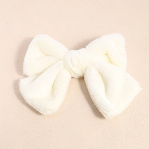 Detailed view of a soft cream plush bow hair clip with fluffy texture and central knot