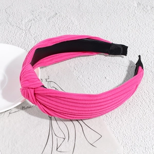 Detail of rose pink ribbed fabric headband with stylish knot on a textured background