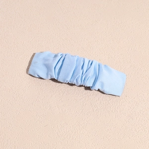 Detailed view of light blue pleated fabric hair clip with soft textured cloth wrap