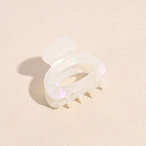 Close-up of small acetate hair claw clip with iridescent finish and resin teeth detail