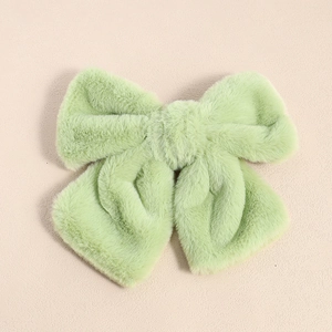 Detail shot of light green plush bow hair clip with soft fuzzy texture and spring metal clasp