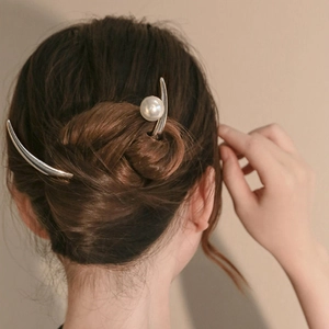 Elegant silver crescent hair pin with a large white pearl in a vintage bun hairstyle