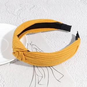 Detail of yellow ribbed knit headband with top knot and non-slip lining on artistic background