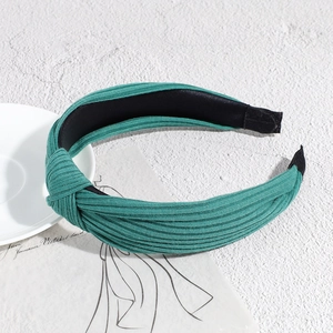 Detail of green ribbed knit fabric headband with a stylish knotted design and non-slip lining