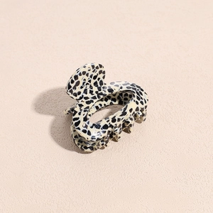 Macro view of spotted acetate claw clip showing polished texture and metal spring detail