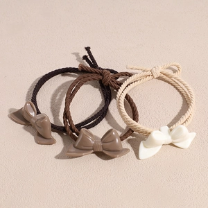 Three-piece hair ties set with resin bows in coffee and cream colors on beige background