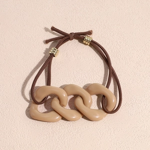Detail of coffee brown elastic hair tie featuring creamy chain links and gold hardware
