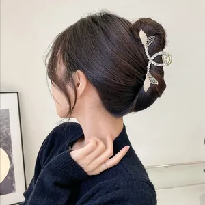 Elegant gold fishtail hair claw clip with white rhinestones worn on a classic updo style