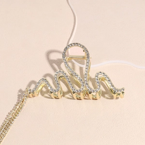 Dettaglio del fermaglio per capelli dorato con strass lucidi e lunghe nappe a onda