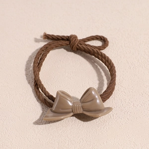 Close-up of a coffee-colored resin bow hair tie with elastic spiral chain band