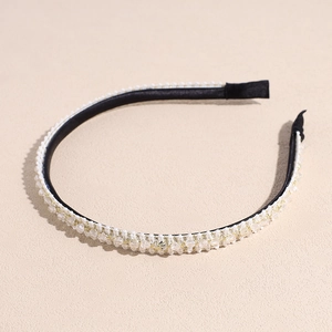 Détail d'un serre-tête noir élégant avec perles transparentes et fils métalliques dorés