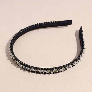 Gros plan d'un serre-tête tressé noir orné de perles de cristal et de fils dorés
