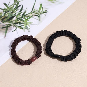 Braune und schwarze elastische Haargummis mit glatten Harzperlen auf hellem Grund