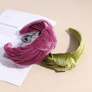 Elegant knotted velvet headbands in burgundy and moss green on minimalist background