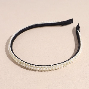 Détail d'un serre-tête noir avec perles blanches et bordure en dentelle crème
