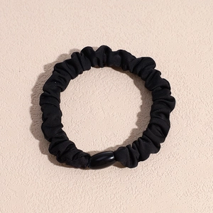 Nahaufnahme des schwarzen Haargummis mit Falten, Gummiband und glatter ovaler Perle