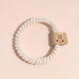 Vue détaillée d'un chouchou spirale blanc avec étiquette en cuir à motif lapin marron