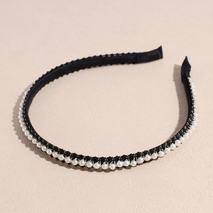 Détail de perles enroulées à la main sur un serre-tête en tissu noir et fils dorés