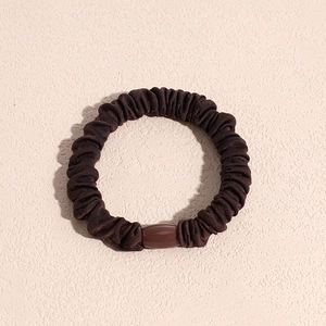 Nahaufnahme brauner elastischer Scrunchie mit Faltenstruktur und dekorativer Harzperle