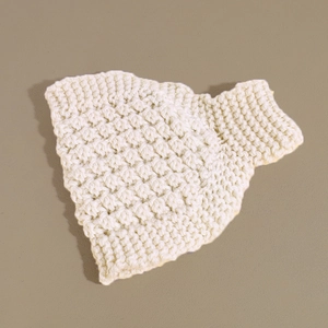 Macro detail of creamy white knitted ear warmer featuring textured thick crochet patterns