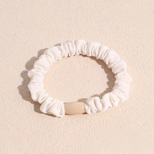 Detailansicht eines cremefarbenen Falten-Scrunchies mit einer glatten ovalen Perle