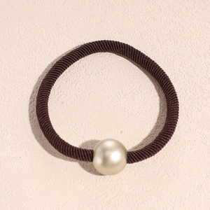 Macro view of brown elastic hair tie featuring a large champagne gold pearl bead