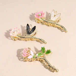Elegante metalen haarklemmen met roos- en libellenontwerpen op een beige achtergrond