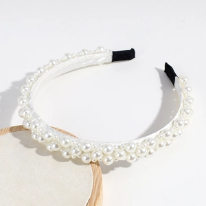Détail d'un serre-tête élégant orné de perles de tailles variées sur du satin blanc