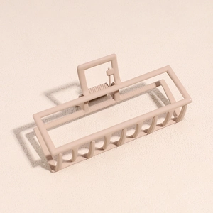 Détail d'une pince à cheveux rectangulaire rose mat en métal pour coiffure élégante